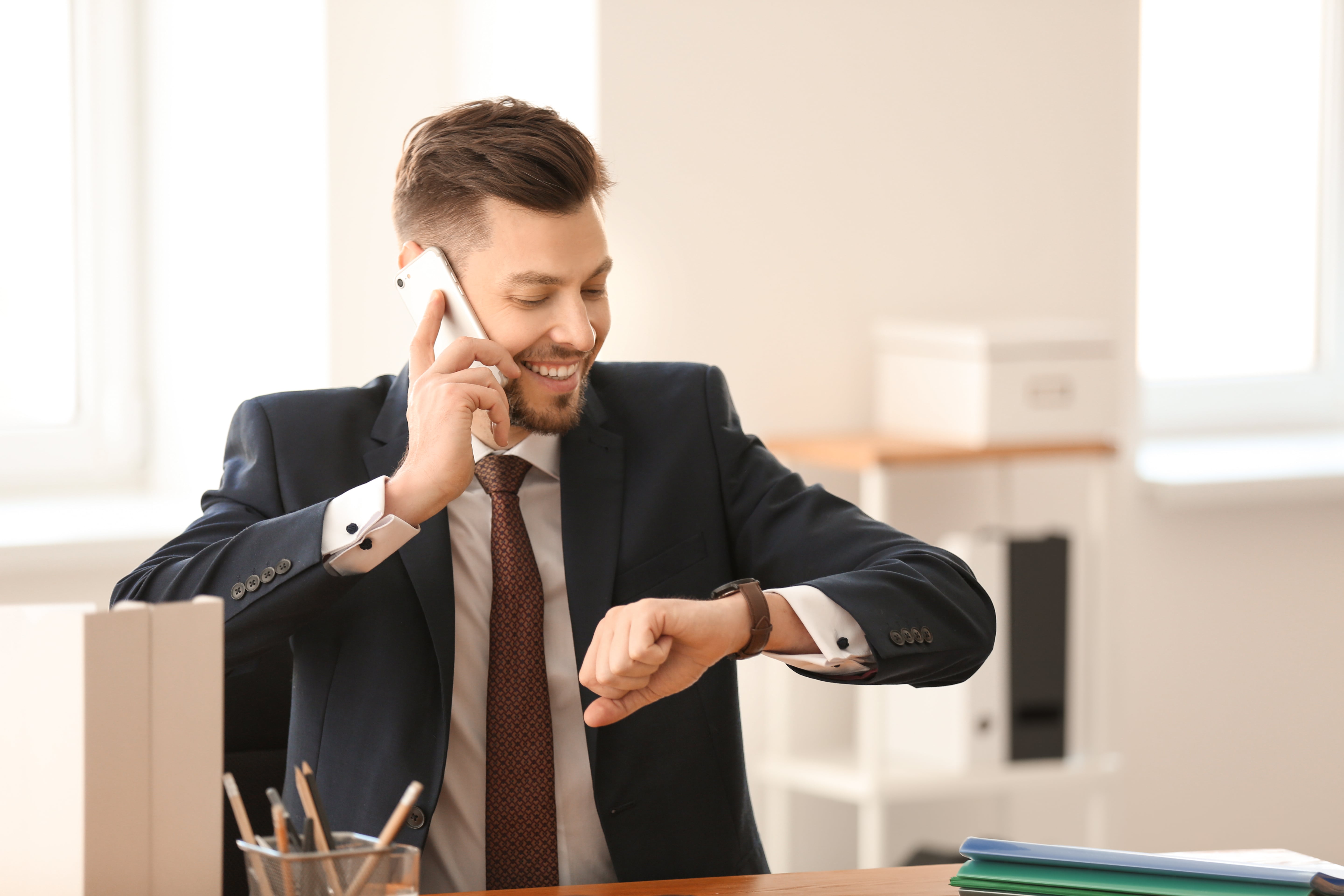 man talking to someone over the phone, looking at the watch